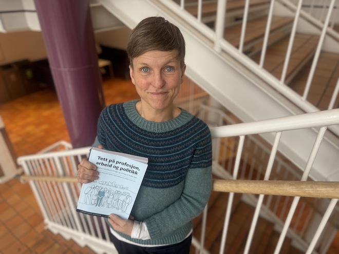 Bildet viser forsker Hanna Ihlebæk i en trapp på campus der hun holder et eksemplar av den nye boken. 