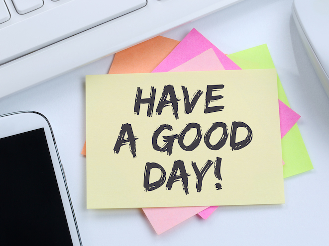Post-it lapp med teksten "Have a good day" klistret på et skrivebord. Illustrasjonsfoto. 