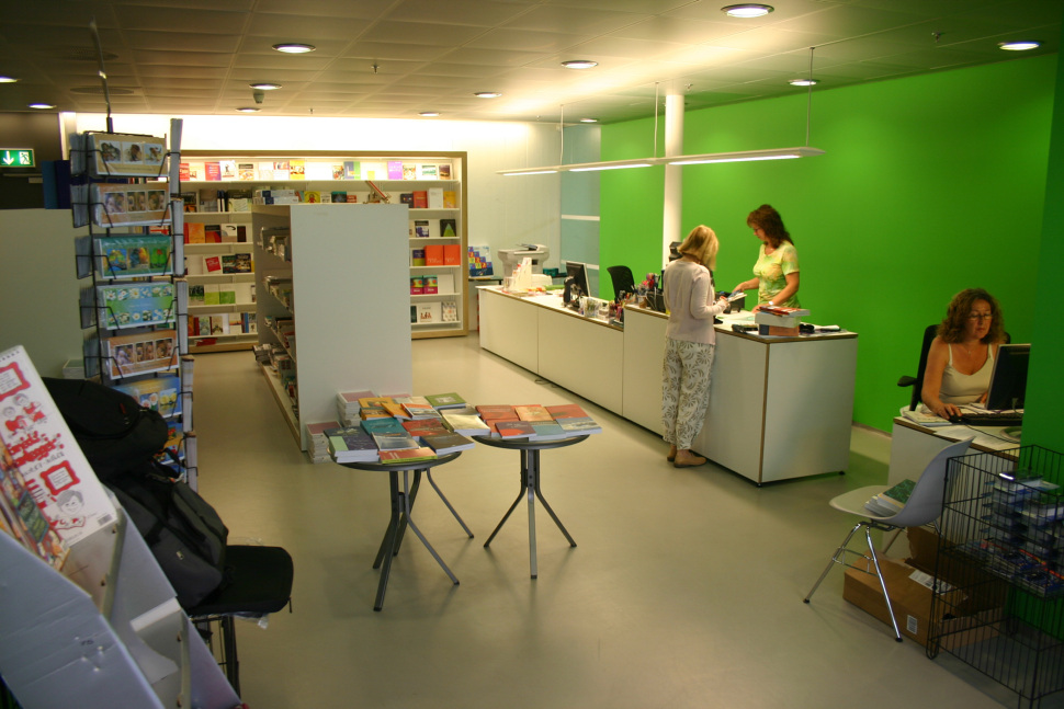 Kunde og to ansatte ved disken i bokhandelen. Foto.