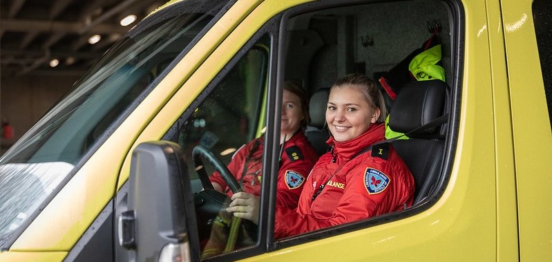 Bilde av to kvinner som sitter foran i en ambulanse.
