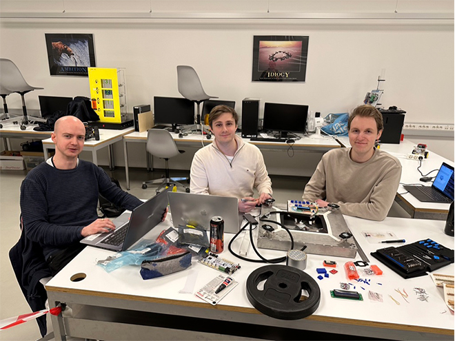 De tre prosjektdeltakerne Andreas Mathisen, Stian Larsen og Simen Johan Kjærstad sitter ved bordet.