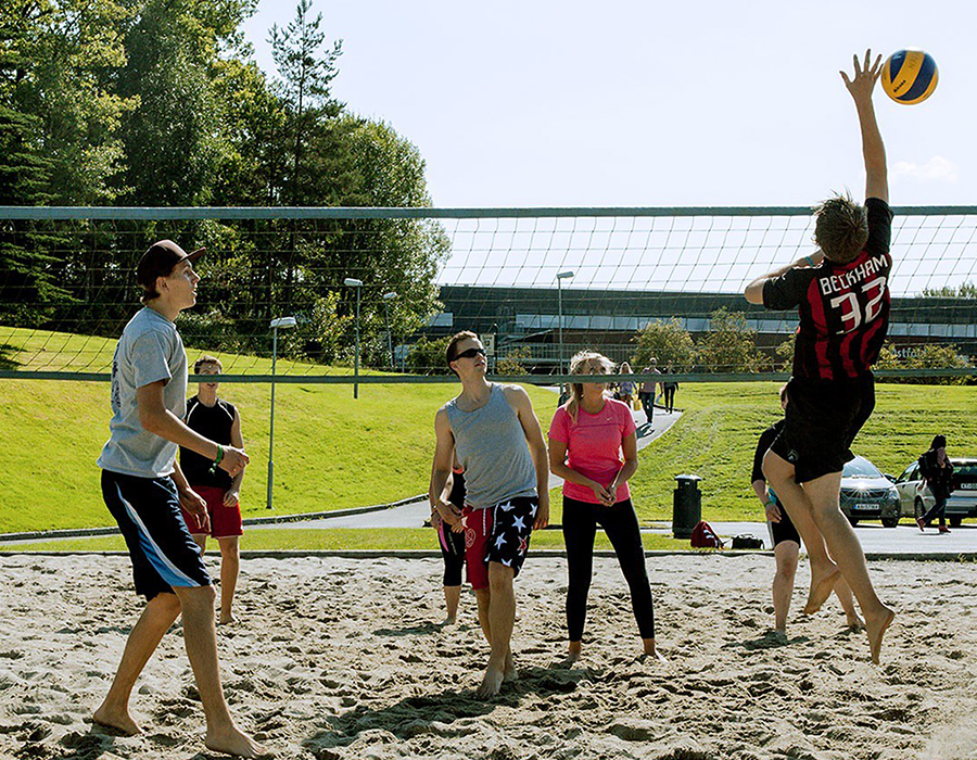 Bildet viser noen som spiller volleyball på campus.