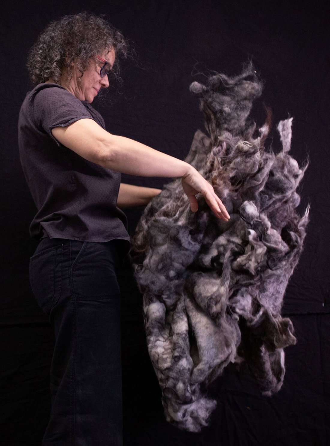 Bilde av forsker i arbeid med en stor mengde ull
