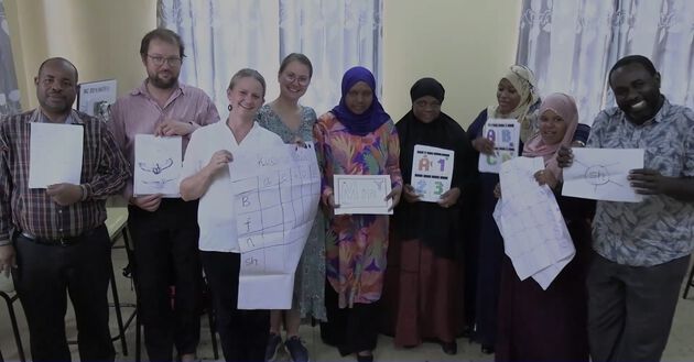 Bildet viser et bilde av de ni prosjektdeltakerne i Noza. Alle holder et ark i hånden.