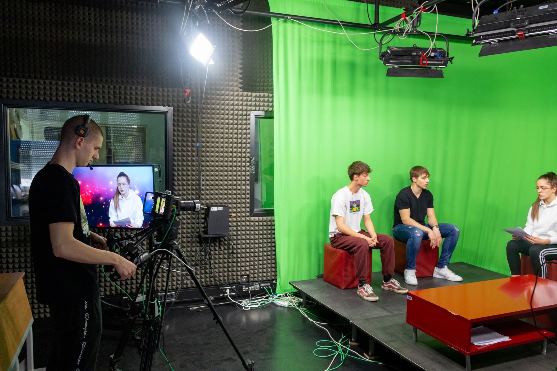 Three students in front of a green screen being filmed