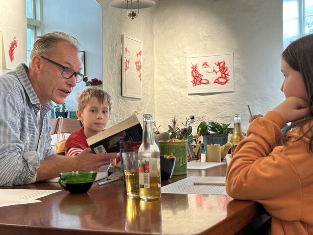 Ein mann og to barn arbeider med omsetjing av ei bok av Roald Dahl.
