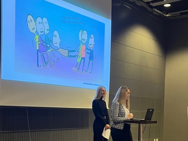 Veronica Knigge og Lin Ramberg holder innlegg under konferansen. På skjermen bak dem er et bilde som på en humoristisk måte illustrerer at det er viktig å samarbeidet om studentene under utdanningen. På bildet står teksten: "Nå er det viktig at vi drar Lasse sammen".