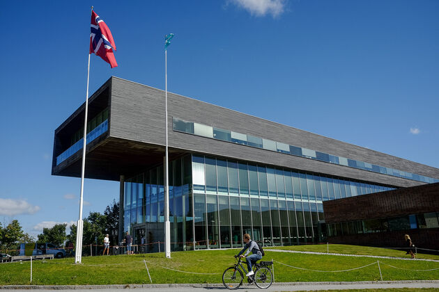 Bildet viser syklist som passerer utenfor høgskolens campus i Halden. 