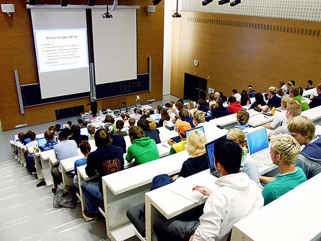 Bildet viser et auditorium med mange studenter som ser på en lysbildepresentasjon